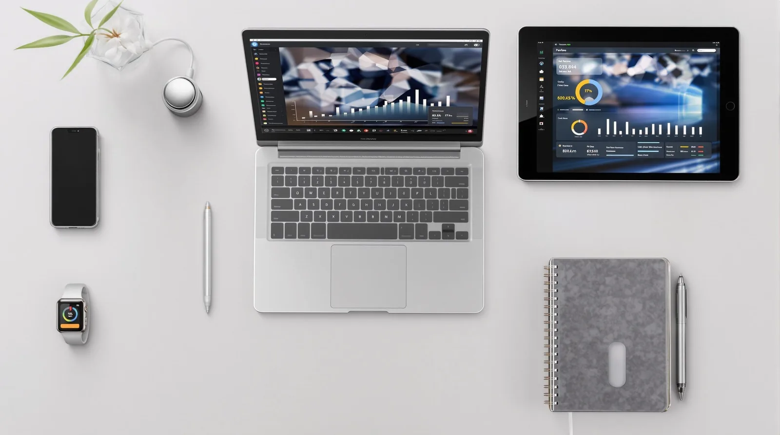 Flat lay of a workspace featuring a laptop, tablet, smartphone, smartwatch, pen, and notebook with modern design elements.